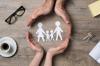 Close up of female and male hands protecting a paper chain family to show concept of family and population.